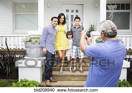 Stock Image - Older man taking picture of family. Fotosearch