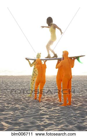 Stock Image - People dressed in strange costumes holding surfboard. Fotosearch
