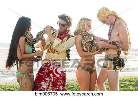 Stock Photography - People looking at boa constrictors on beach. Fotosearch