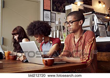 Stock Image - People using technology in coffee shop. Fotosearch