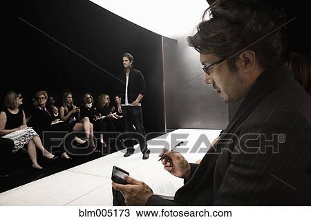 Stock Image - People watching model on runway in fashion show. Fotosearch