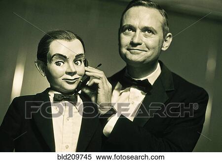 Performer holding cell phone to ventriloquist dummy View Large Photo Image Stock Photography - Performer holding cell phone to ventriloquist dummy. Fotosearch