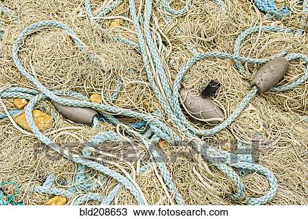 Stock Image - Pile of fishing nets, floats and blue rope on the quayside at Dungeness. Fotosearch