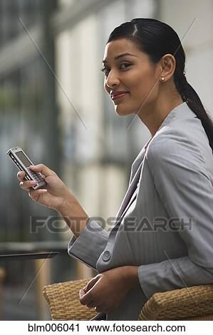 Stock Image - Pilipino businesswoman text messaging on cell phone. Fotosearch