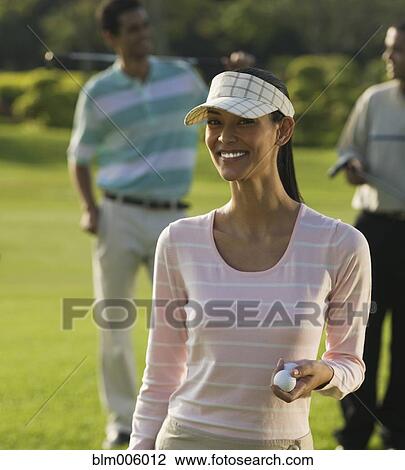 Stock Image - Pilipino woman golfing with friends. Fotosearch
