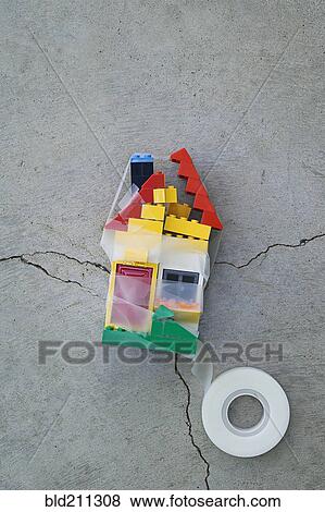 Stock Photo - Plastic block house taped together on concrete. Fotosearch
