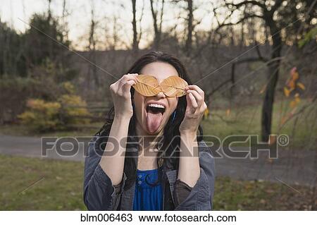 Playful Caucasian woman with leaves covering her eyes View Large Photo Image Stock Image - Playful Caucasian woman with leaves covering her eyes. Fotosearch
