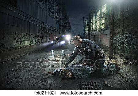 Stock Image - Policeman arresting man on city street. Fotosearch