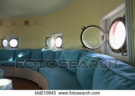 Stock Image - Port hole windows in round lighthouse living room. Fotosearch