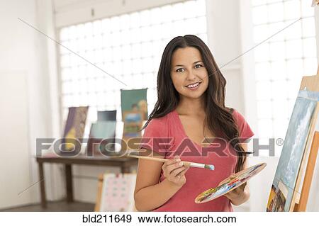 Portrait of smiling woman painting at easel View Large Photo Image Stock Photo - Portrait of smiling woman painting at easel. Fotosearch