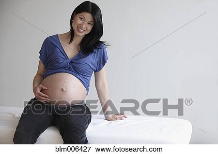 Pregnant Asian woman holding stomach View Large Photo Image Stock Photo - Pregnant Asian woman holding stomach. Fotosearch
