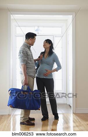 Stock Image - Pregnant Chinese woman and husband leaving for hospital. Fotosearch