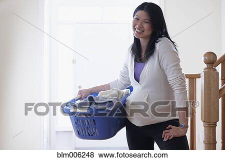 Stock Photo - Pregnant Chinese woman holding laundry basket. Fotosearch