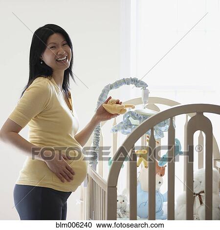 Stock Image - Pregnant Chinese woman in nursery. Fotosearch