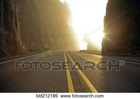Stock Photo - Rural road cutting through mountains. Fotosearch