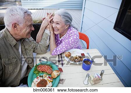 Stock Image - Senior Caucasian couple eating lunch on patio. Fotosearch