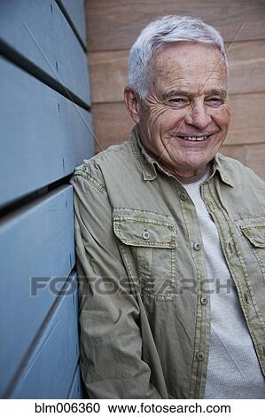 Stock Image - Senior Caucasian man leaning against wall. Fotosearch