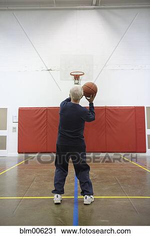 Stock Image - Senior Caucasian man playing basketball. Fotosearch
