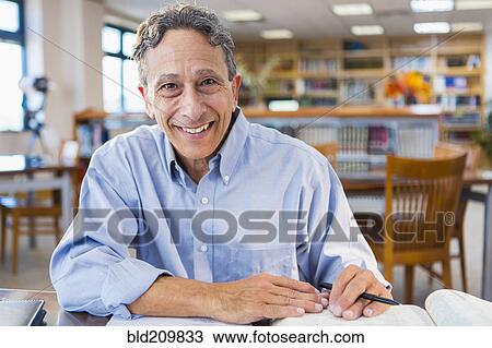 Stock Image - Senior man working in library. Fotosearch