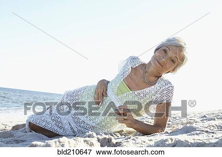 Stock Photo - Senior woman laying on tropical beach. Fotosearch