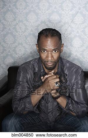 Stock Image - Serious man in elegant clothing sitting on sofa. Fotosearch