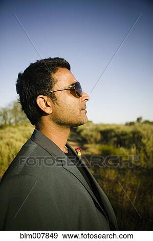 Stock Photo - Serious mixed race man in field. Fotosearch