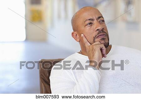 Stock Image - Serious mixed race man thinking in art gallery. Fotosearch