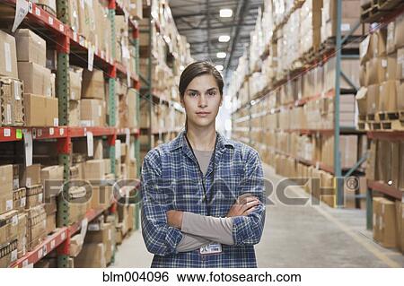 Stock Photograph - Serious mixed race woman with arms crossed in warehouse. Fotosearch