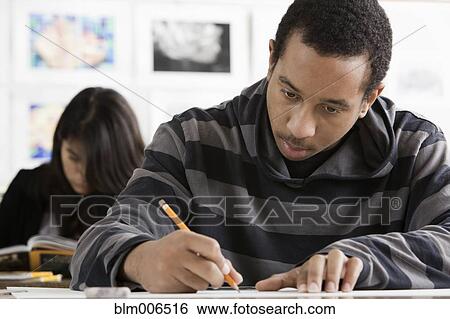 Stock Photograph - Serious student writing in classroom. Fotosearch