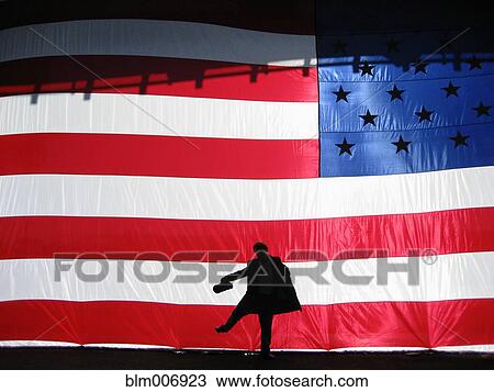 Stock Image - Silhouette of man behind American flag. Fotosearch