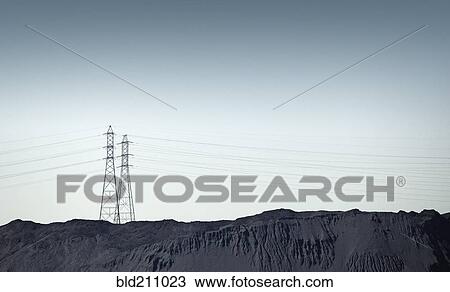 Stock Image - Silhouette of power lines over rocky landscape. Fotosearch