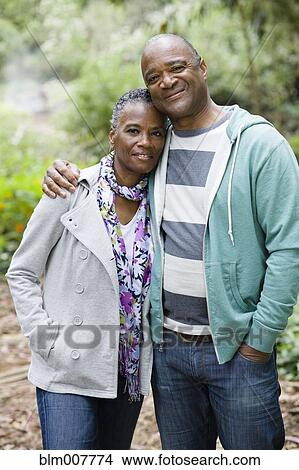 Picture - Smiling African American couple hugging in park. Fotosearch