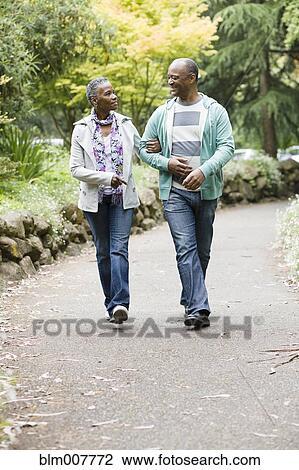 Stock Image - Smiling African American couple walking in park. Fotosearch