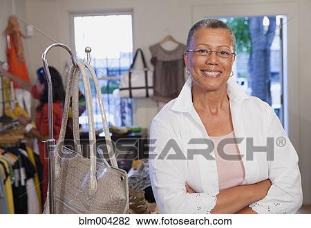 Smiling African woman with arms crossed in clothing store View Large Photo Image Stock Image - Smiling African woman with arms crossed in clothing store. Fotosearch