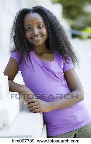 Smiling Black girl leaning on wall View Large Photo Image Stock Photo - Smiling Black girl leaning on wall. Fotosearch