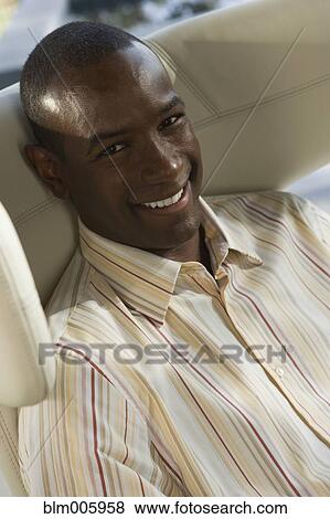 Stock Photo - Smiling Black man sitting in chair. Fotosearch