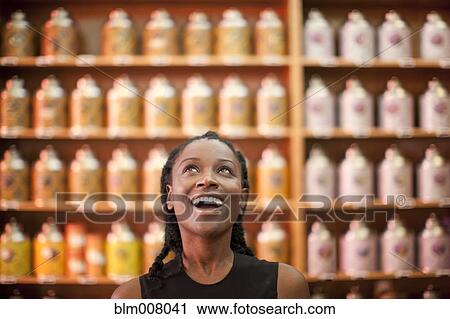 Smiling Black woman looking up in shop View Large Photo Image Stock Image - Smiling Black woman looking up in shop. Fotosearch
