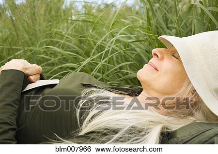 Stock Photograph - Smiling Caucasian woman sleeping in grass. Fotosearch