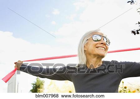 Stock Photo - Smiling Caucasian woman stretching with resistance band. Fotosearch