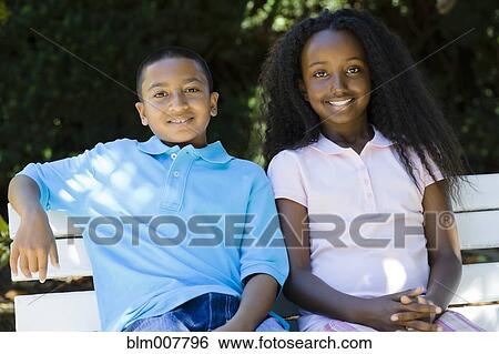 Smiling children sitting on park bench View Large Photo Image Stock Photograph - Smiling children sitting on park bench. Fotosearch