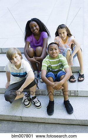 Stock Image - Smiling children sitting on steps together. Fotosearch
