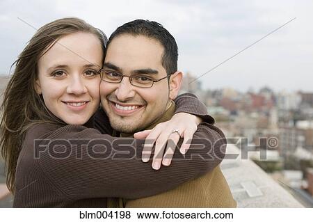 Stock Photo - Smiling couple hugging on rooftop. Fotosearch