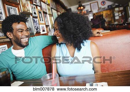 Stock Photo - Smiling couple sitting in diner booth. Fotosearch