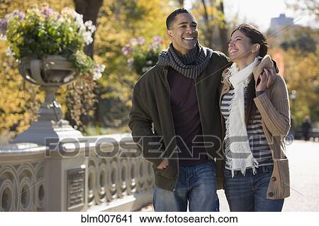 Stock Image - Smiling couple walking in park. Fotosearch