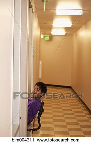 Stock Image - Smiling Hispanic boy leaning out into corridor. Fotosearch