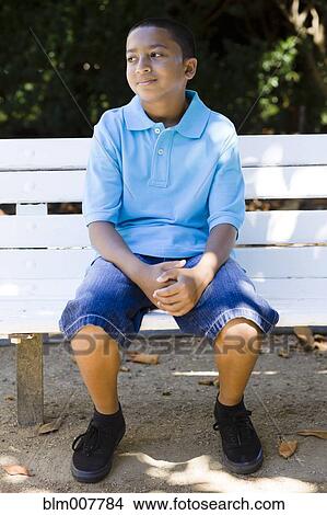 Picture - Smiling mixed race boy sitting in park. Fotosearch