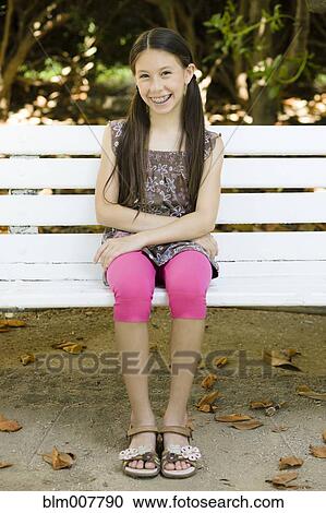 Smiling mixed race girl sitting on park bench View Large Photo Image Stock Image - Smiling mixed race girl sitting on park bench. Fotosearch