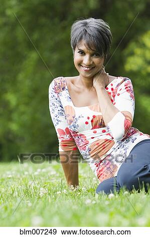 Smiling mixed race woman sitting in field View Large Photo Image Stock Photo - Smiling mixed race woman sitting in field. Fotosearch
