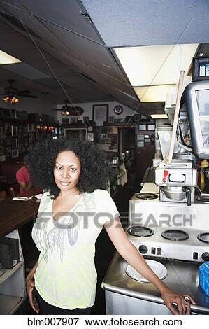 Stock Photo - Smiling mixed race woman standing behind counter in diner. Fotosearch