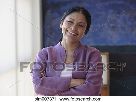 Stock Image - Smiling mixed race woman with arms crossed. Fotosearch
